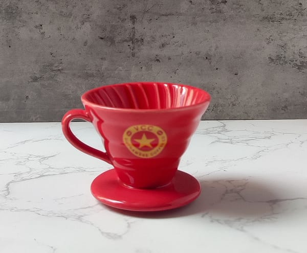 A red ceramic V60 brewer with a circular Vietnamese Coffee Co. logo.
