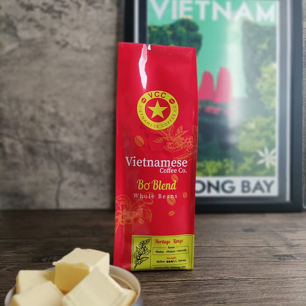 A bag of Bo blend Vietnamese coffee. Pictured with a dish with knobs of butter and a picture of Ha Long bay.